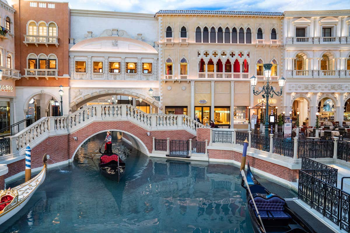 Gondolier on a gondola floating down the canal underneath a bridge in the Grand Canal Shoppes at The Venetian Resort.