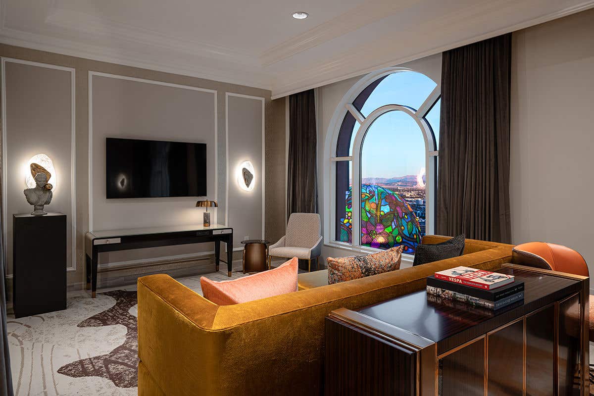 A modern living room with a mustard yellow sofa, flat-screen TV, arched window, and a Sphere view. 