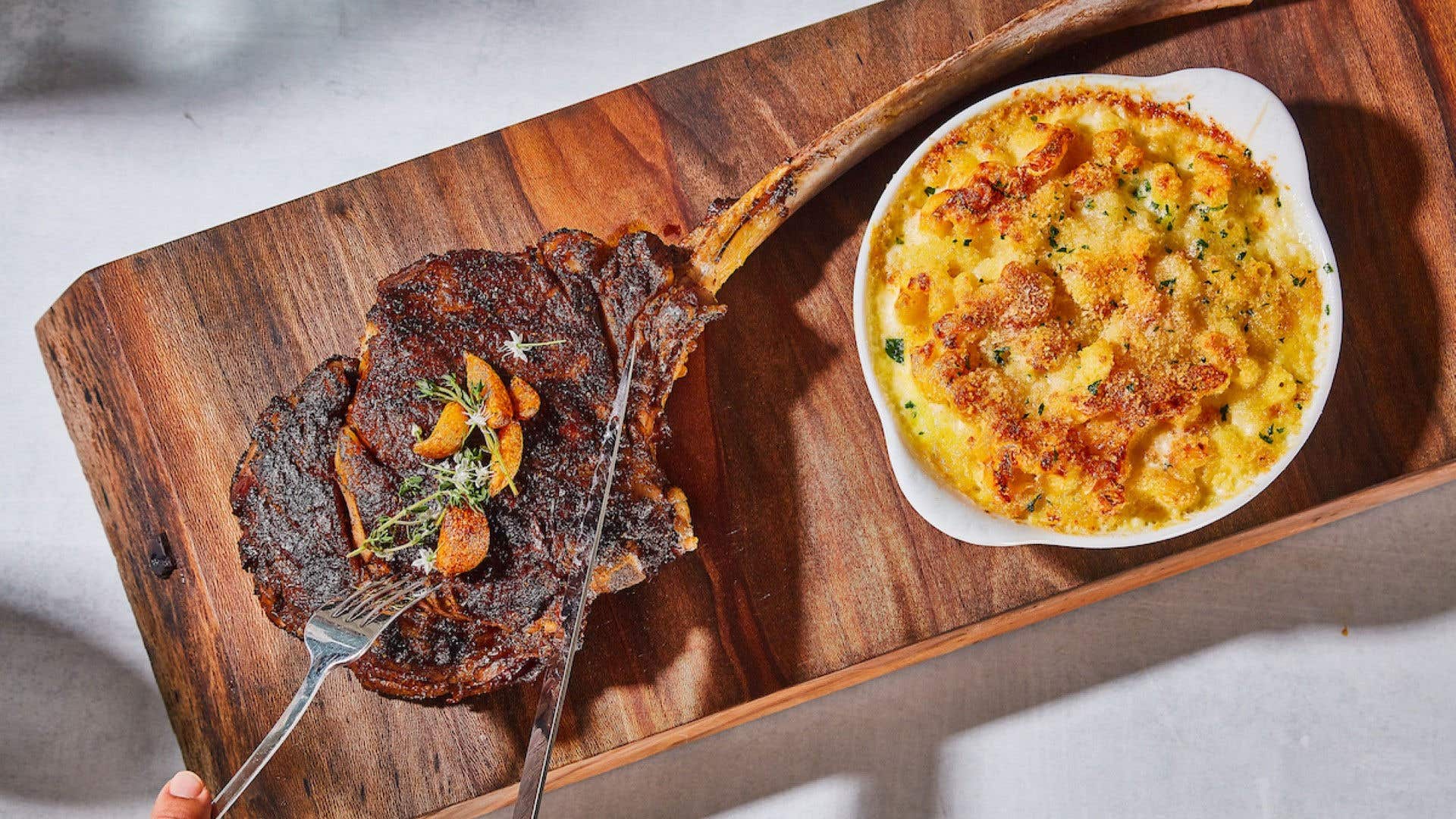 Bone-in tomahawk ribeye paired with golden baked cavatappi mac and cheese.