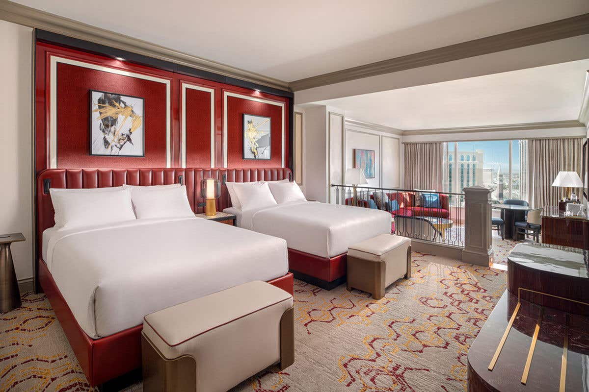 A suite with two queen beds, with accents of red next to the bed