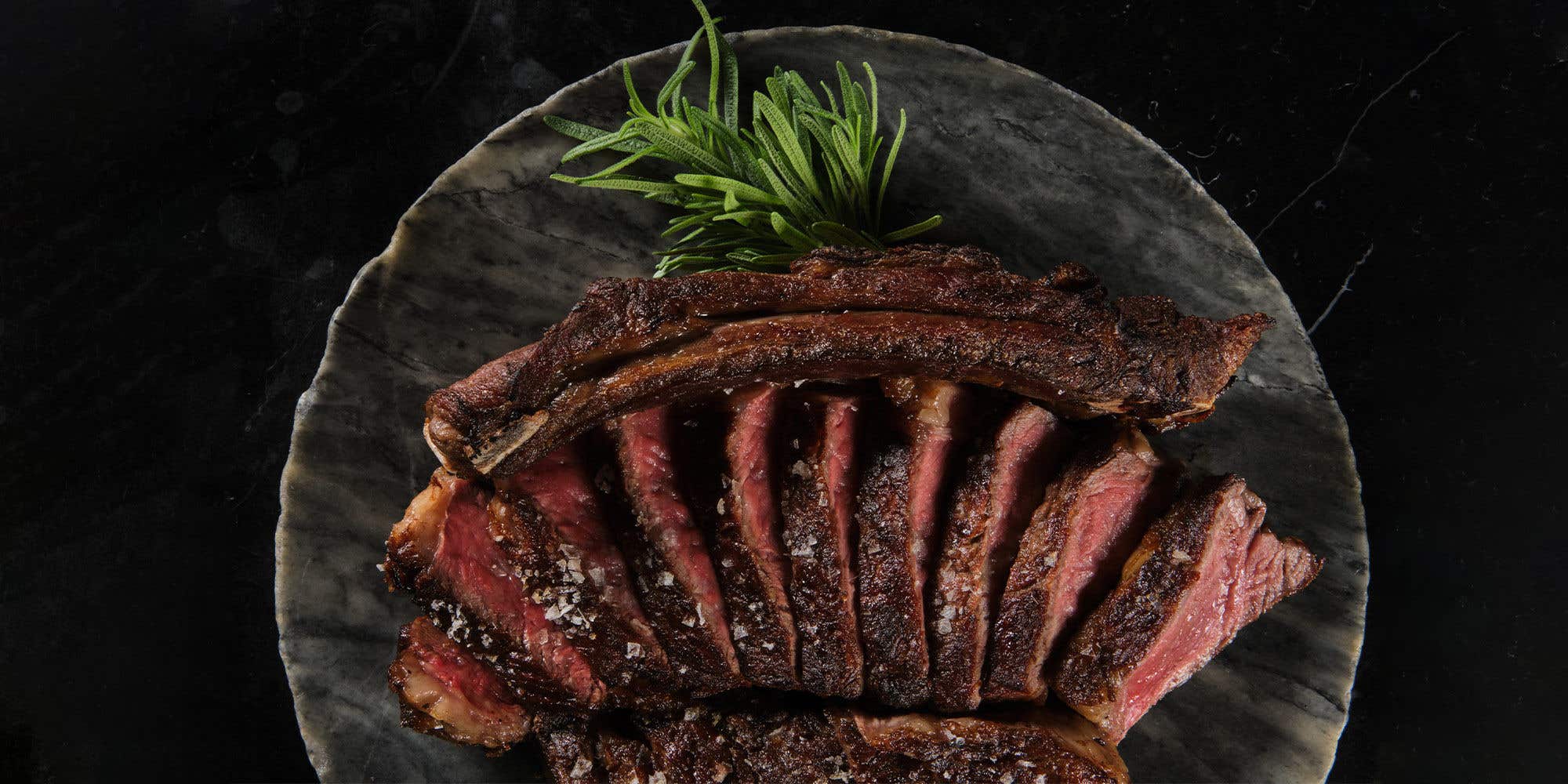 Cooked slices of meat laid out on a plate with the bones laid above it. 