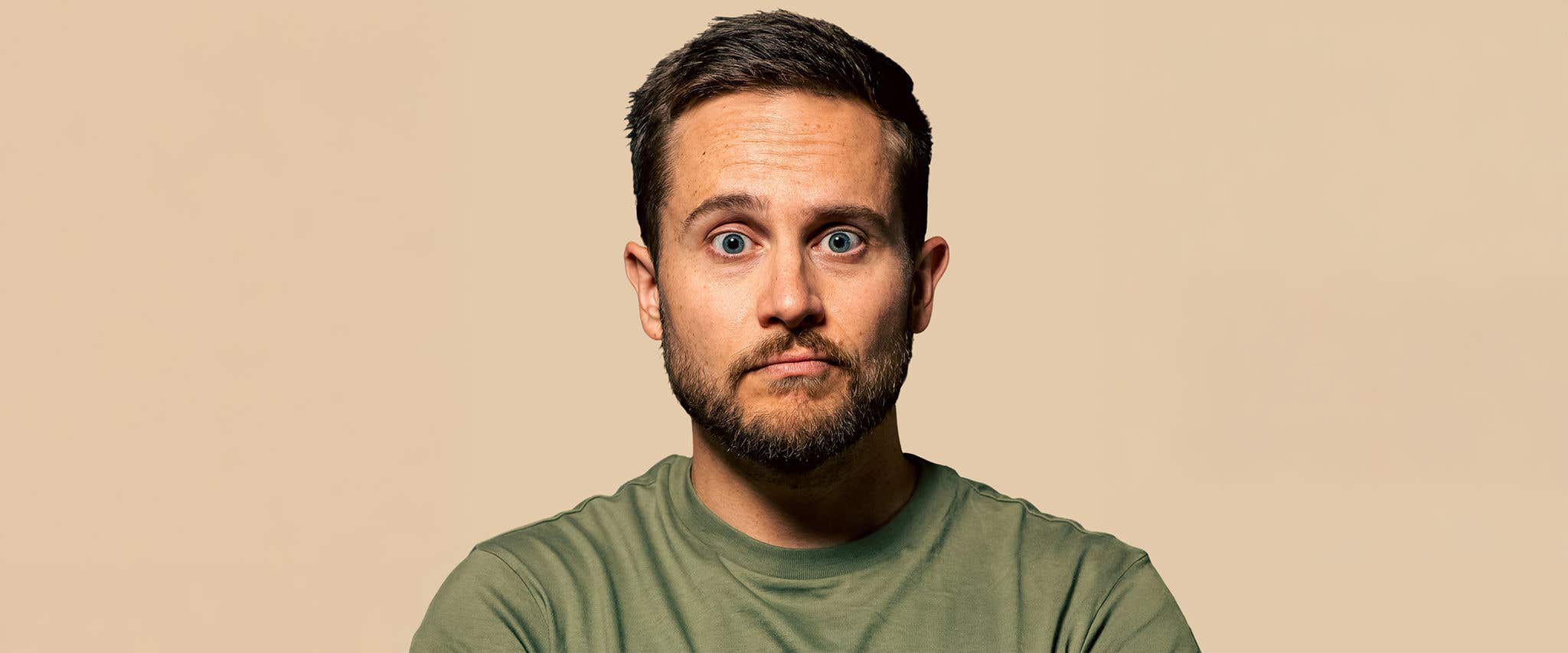 Zoltan Kaszas wearing a green shirt looking at the camera in front of a neutral background.