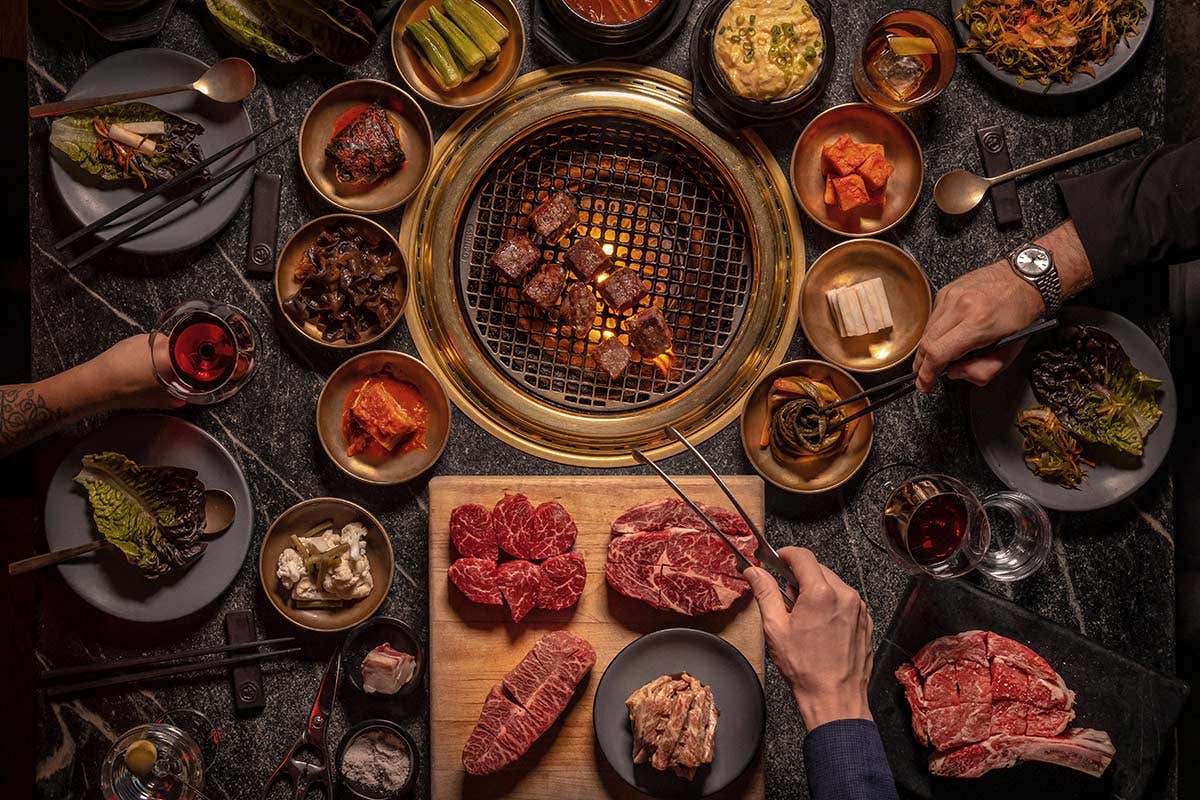 People grilling meat at their table and drinking wine